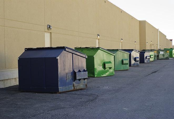 a truck unloading construction waste into a dumpster in Minot